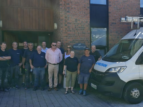 Group of Polygon staff members posing together outside the Wellsprings building next to a Polygon company van