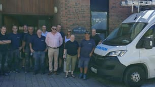Group of Polygon staff members posing together outside the Wellsprings building next to a Polygon company van
