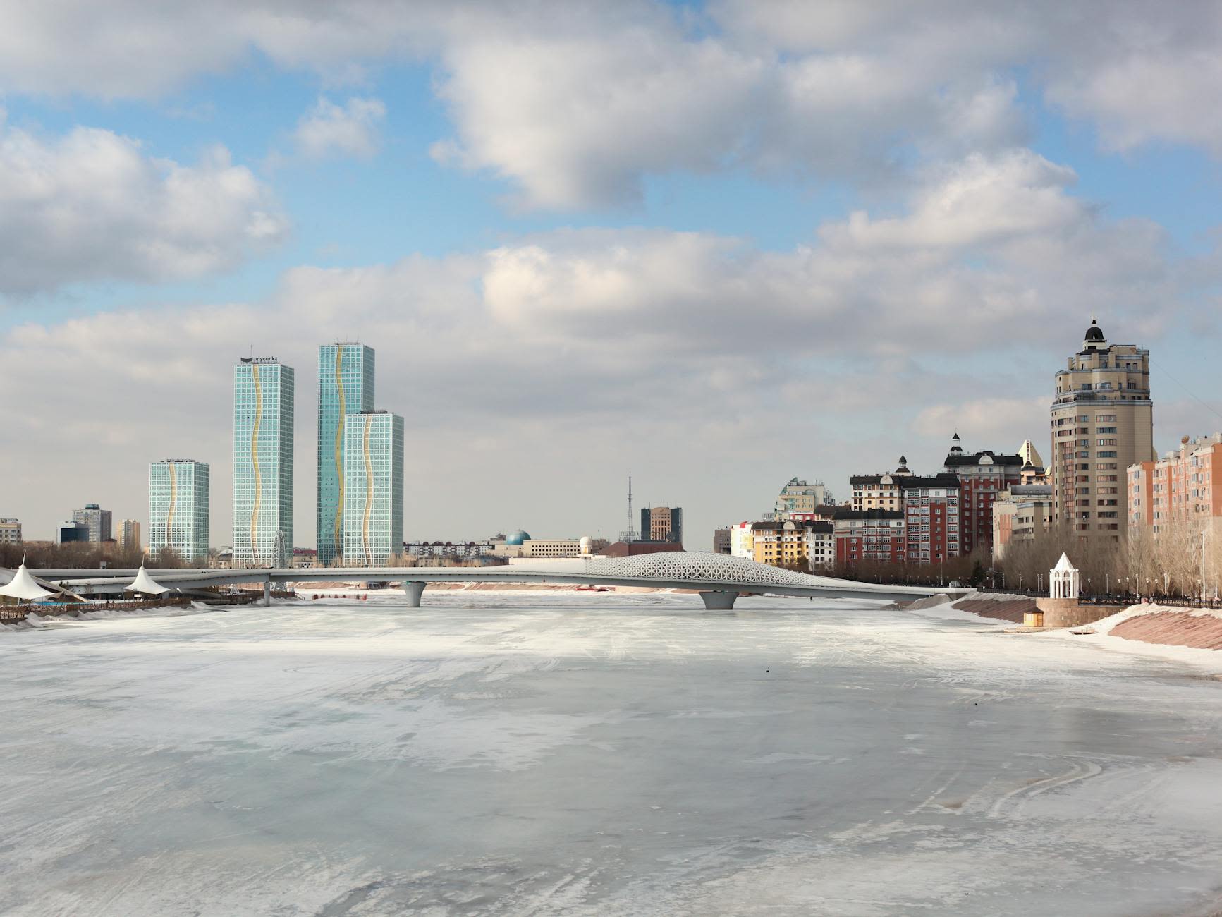 Астана, Казахстан: Обзор столицы

**Астана** — столица Казахстана. С населением 1 622 245 человек, это второй по величине город страны после Алматы, который был национальной столицей до 1997 года. Город расположен на берегах реки Ишим в северной части Казахстана.

История Астаны отмечена быстрым ростом, особенно после того, как она стала столицей. Её превращение в современный и спланированный город было осуществлено в соответствии с генеральным планом, разработанным японским архитектором Кишо Курокавой. Сегодня Астана знаменита своей футуристической архитектурой, в которой размещены ключевые государственные учреждения, включая резиденцию Ак Орда, Дом Парламента и Верховный суд. Она стала важным центром культуры, образования и торговли в Казахстане и Центральной Азии.

Город славится своими современными достопримечательностями, включая Байтерек, символизирующий независимость Казахстана, развлекательный центр Хан Шатыр и мечеть Хазрат Султан — одну из крупнейших в Центральной Азии. Дворец мира и согласия, предназначенный для проведения культурных и межрелигиозных мероприятий, подчеркивает роль города как центра диалога и сотрудничества.

10 июня 1998 года Астана была представлена как столица на международном уровне. Город был выбран благодаря нескольким преимуществам: большим городским территориям, выгодному географическому положению, близости к основным экономическим центрам региона, значительному демографическому потенциалу, хорошей транспортной инфраструктуре и относительно благоприятному климату. 16 июля 1999 года Астана была удостоена медали и звания «Город мира» от ЮНЕСКО.

## Знаковые достопримечательности

- Ак Орда — резиденция Президента Республики Казахстан
- Астанская большая мечеть — крупнейшая мечеть в Центральной Азии, завершена в 2022 году
- Байтерек — смотровая башня высотой 105 м, построенная в 1996 году. Это популярная туристическая достопримечательность, символизирующая перенос столицы Казахстана из Алматы в Астану.

**Дворец Ак Орда**

Знаменитая резиденция президента Назарбаева, Ак Орда, что означает «белый штаб» на казахском, спроектирована по образцу Белого дома. Она включает здания Мажилиса и Сената, Верховного суда и министерств, а также Национальную библиотеку и архив, которые все можно увидеть в административном центре столицы.

**Бульвар Вода-Зелень**

На главной площади города можно увидеть многочисленные водные каскады и фонтаны.

**Центральная площадь**

Одна из старейших частей города, центральная площадь — дом старых зданий парламента и многих других исторических достопримечательностей, а также множества фонтанов.

Хотя Астана — город всего 15-летней истории, она быстро завоевала известность в Центральной Азии. Хотя с архитектурной точки зрения планировка может показаться разрозненной, цель президента Назарбаева и архитекторов со всего мира заключалась в создании города, отражающего амбициозное будущее Казахстана как развивающейся страны и демонстрирующего мост между восточными и западными стилями.

Астана, столица Казахстана, расположена вдоль реки Ишим (Есиль). Она находится в малонаселённой северо-центральной части Казахстана и в географическом центре обитаемой территории страны. Город был выбран столицей отчасти для стимулирования развития по всей стране и распространения роста за пределы юго-восточного угла, где расположен Алматы, крупнейший город.

Город был основан в 1824 году как русский военный форпост и стал административным центром в 1868 году. Население достигло 33 000 человек, когда в 1939 году он стал центром области. Значение города значительно возросло в советский период благодаря кампании правительства по освоению целины и залежных земель в середине 1950-х годов — Целиноград по-русски означало «Город целинных земель» — и роли города как столицы края, объединявшего пять северных провинций Казахской ССР в 1960–1965 годах.

Название города было изменено на Акмолу («Белая могила») в 1992 году после обретения Казахстаном независимости. В 1994 году правительство Казахстана решило перенести национальную столицу из Алматы в Акмолу, процесс был завершён в 1997 году, а название города снова изменили на Астану («Столица») на следующий год.

Президент Казахстана Нурсултан Назарбаев потратил значительные суммы нефтяных доходов страны на радикальное расширение и реконструкцию Астаны. Правительство наняло японского архитектора Курокаву Кишо для проектирования широких проспектов и зданий в сине-золотых тонах, включая Президентский дворец. Назарбаев также привлек британского архитектора Нормана Фостера для проектирования Дворца мира и согласия — пирамиды высотой 62 метра, в которой, среди прочего, есть библиотека и оперный театр.

Астана, столица Казахстана, — самый современный и стильный город страны, привлекающий посетителей уникальными архитектурными решениями. Город расположен на берегах реки Ишим, которая делит его на правый и левый берега. Левый берег особенно впечатляющ: там находятся все выдающиеся сооружения.

В 1997 году в Астане проживало около 300 000 человек на площади 258 квадратных километров. К 2016 году население столицы превысило один миллион человек, а город расширился до почти 800 квадратных километров.

Символом казахской столицы является **монумент Байтерек**, представляющий дерево жизни с мощными корнями и устремлением в небо. В его центре — глобус с автографами представителей 17 мировых религий. Байтерек предлагает самые потрясающие виды на Астану.

Крупнейший флаг Казахстана, расположенный на высоте 110 метров и занимающий площадь 450 квадратных метров, виден из любой точки Астаны.

Ещё одна заметная достопримечательность столицы — небоскрёб Abu Dhabi Plaza в 75 этажей, самый высокий в Центральной Азии. Комплекс состоит из пяти башен, самая высокая из которых достигает 320 метров, и включает жилые, гостиничные, деловые помещения, а также торгово-развлекательные зоны. Многие секции Abu Dhabi Plaza уже открыты, и на начало 2022 года комплекс завершён на 97%.

Я прошёл почти четыре километра на восток от центра города, чтобы добраться до Площади Независимости — главной общественной площади Астаны. Основанная в 2009 году, площадь является домом для нескольких крупных достопримечательностей, включая Монумент Казахстан Эли — величественный символ независимости нации — и Дворец Независимости, где проводятся государственные мероприятия, такие как форумы, встречи и конвенции.