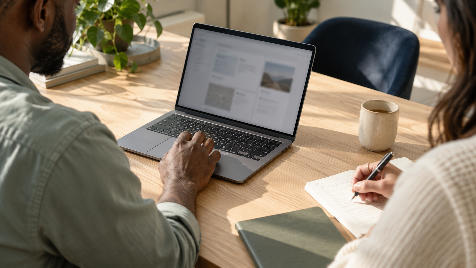 Conceptual image of two people reviewing work at a laptop in a sunlit workspace