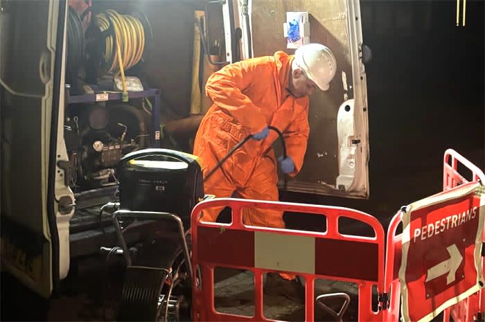 Drainage engineer on a night time call out unblocking a blocked drain