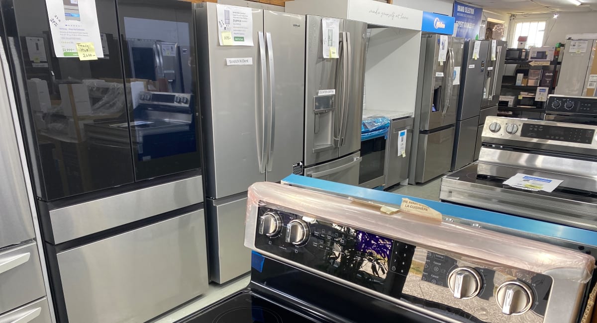Black-glass and stainless French-door refrigerators, one marked Scratch N Dent, lined up at Barn Appliances
