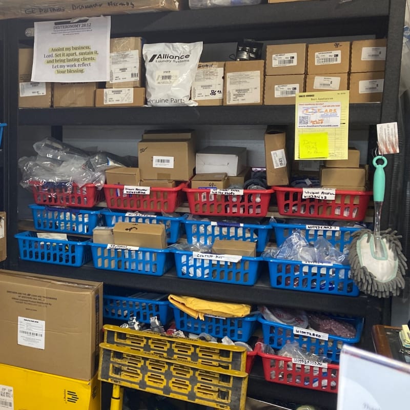 Red and blue bins labeled with part numbers for washer timers, pressure switches and clutch kits at Barn Appliances