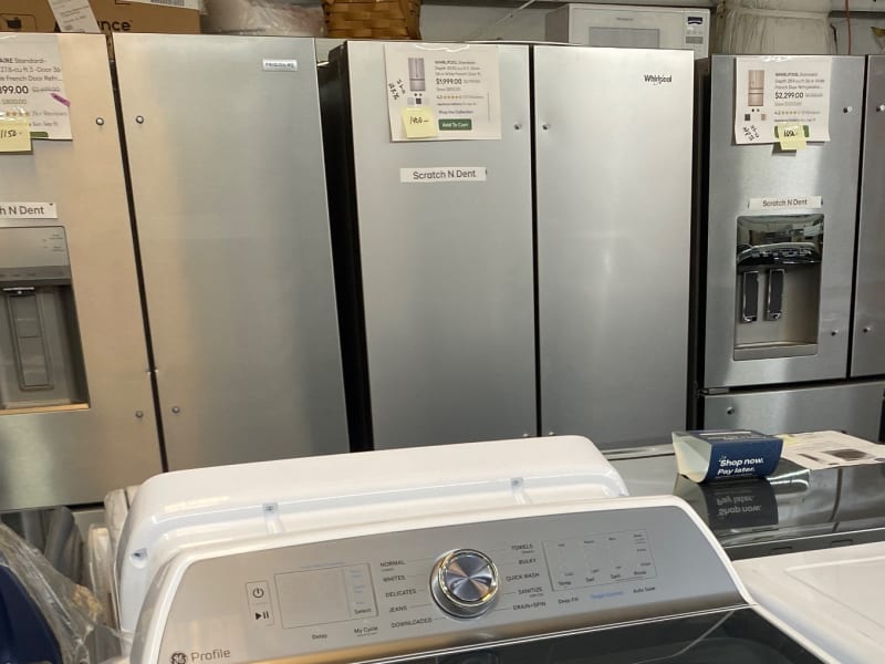 Stainless French-door refrigerators labeled Scratch N Dent behind the control panel of a GE Profile washer at Barn Appliances