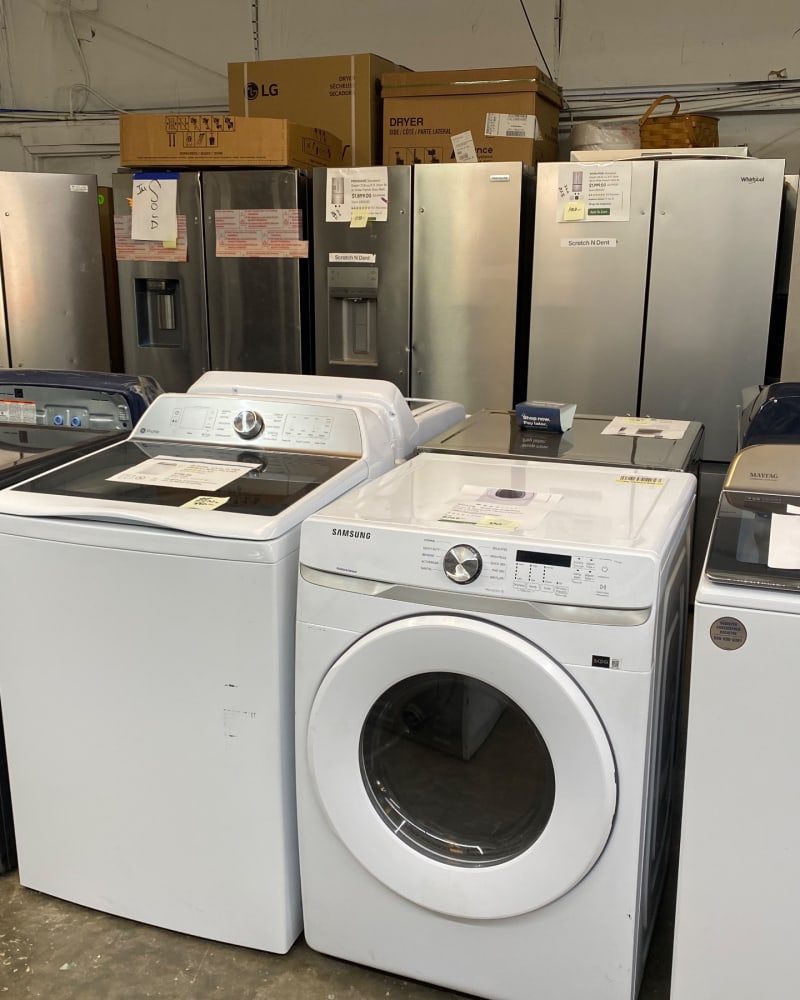 A Samsung dryer and a Maytag washer marked Scratch N Dent in front of stainless refrigerators