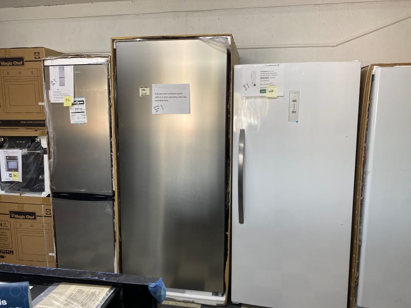 Stainless and white upright freezers standing in their opened shipping cartons at Barn Appliances