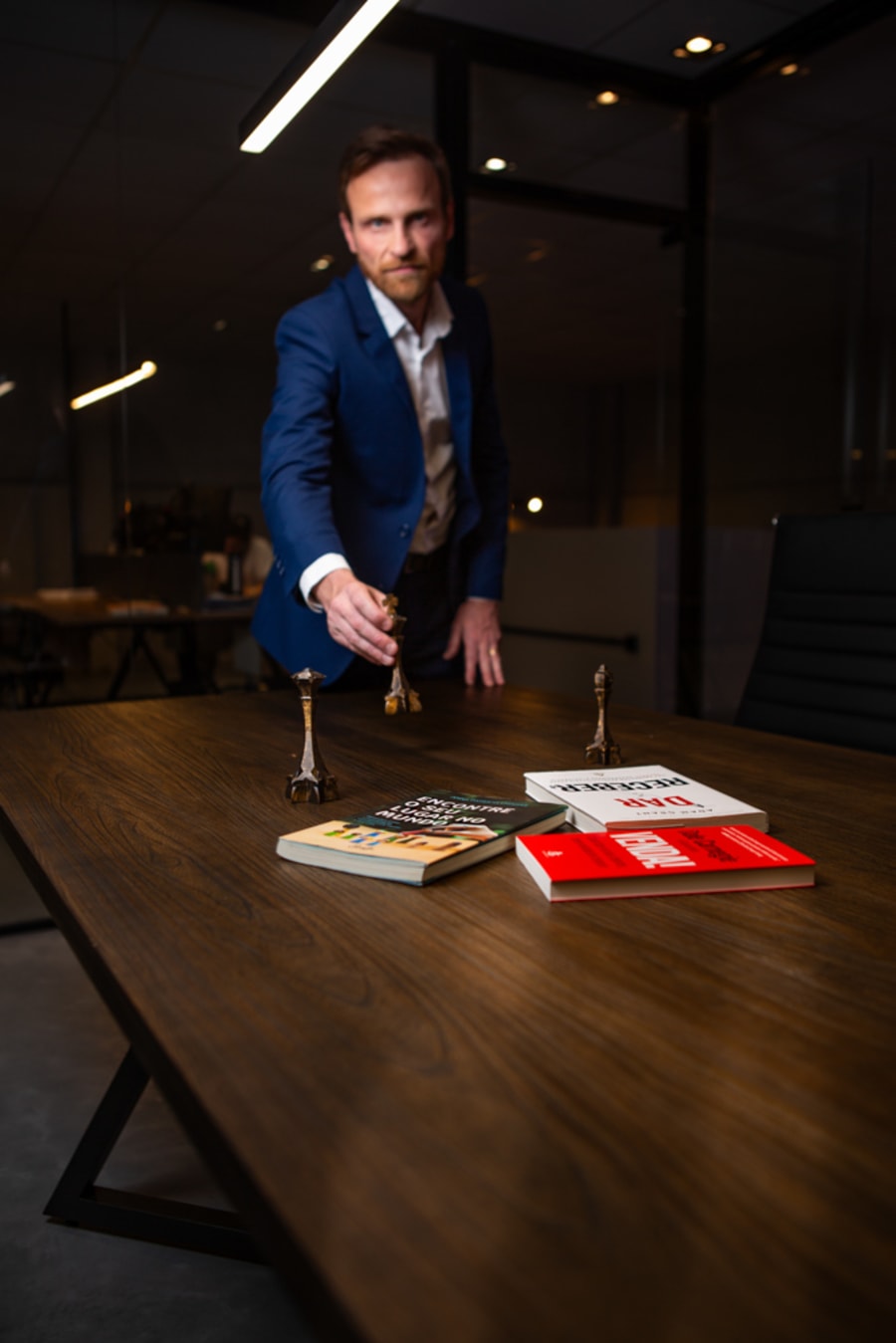 Advogado de blazer azul em pé em escritório com estantes ao fundo, em retrato corporativo