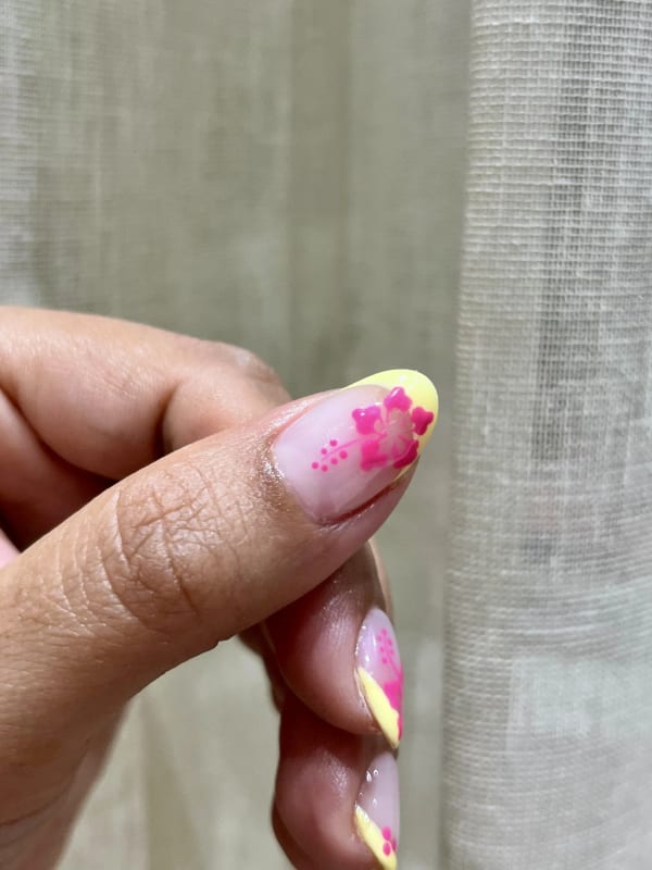 a person holding a pink and yellow nail
