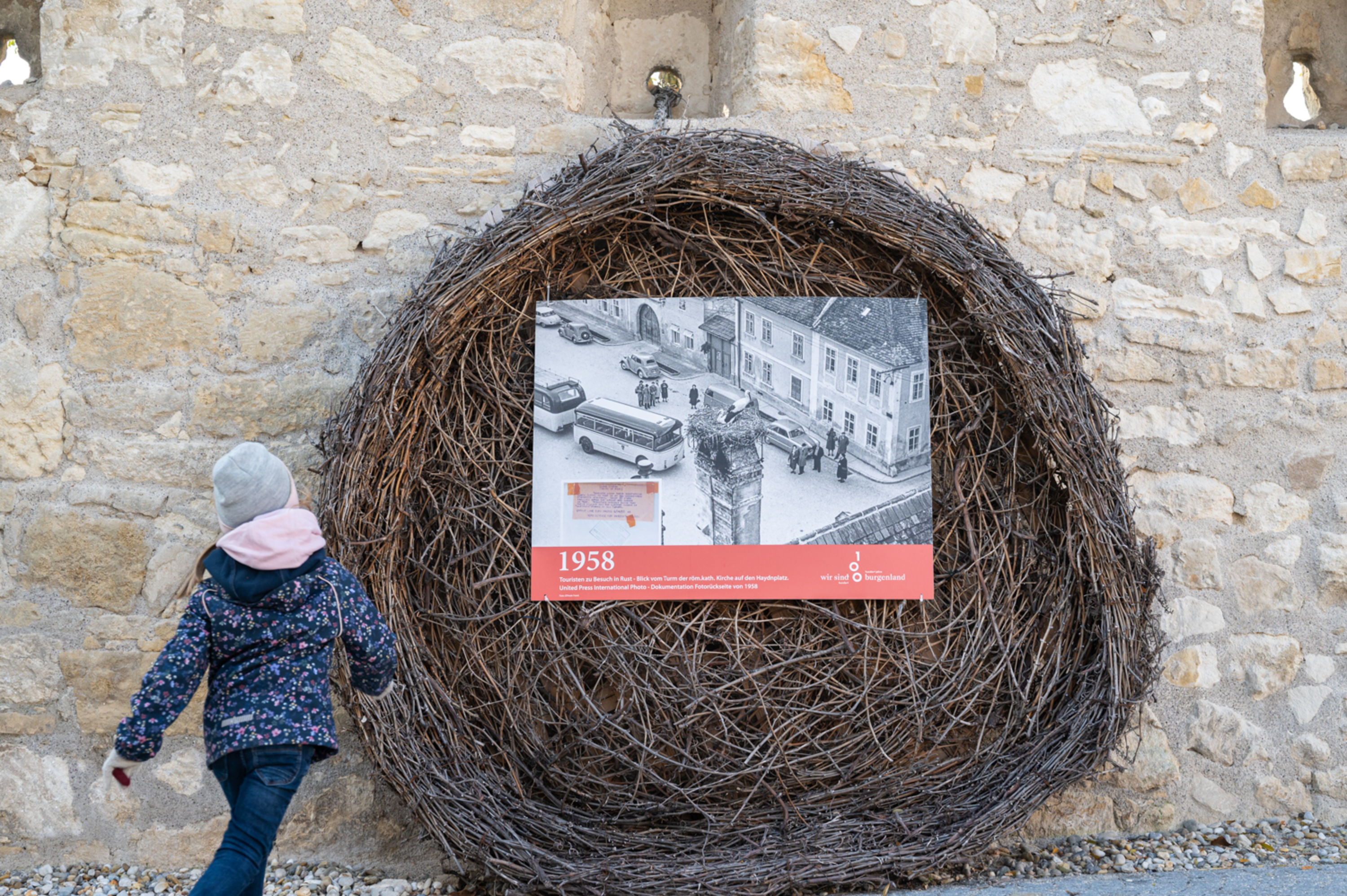 Storchennest in Rust an der Stadtmauer mit Kind davor