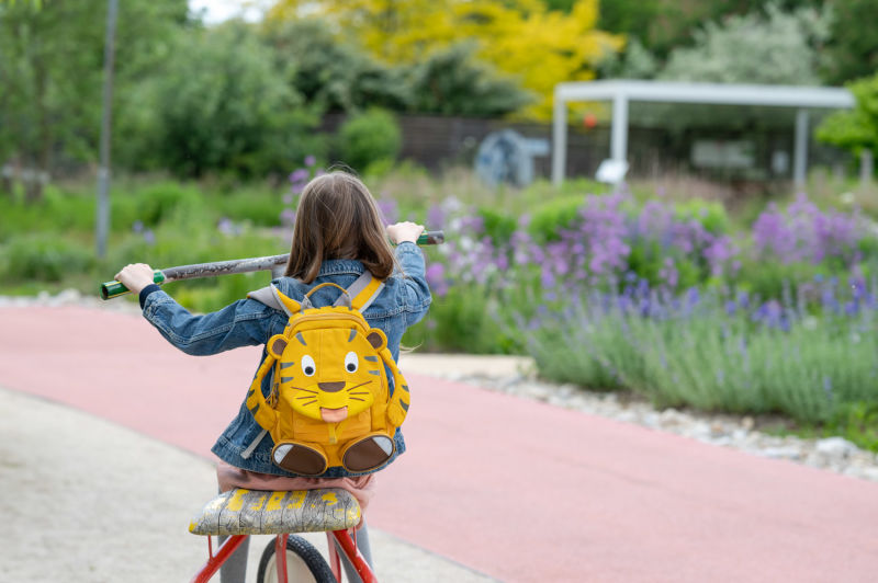 Kind auf großem Roller bei die GARTEN TULLN von hinten