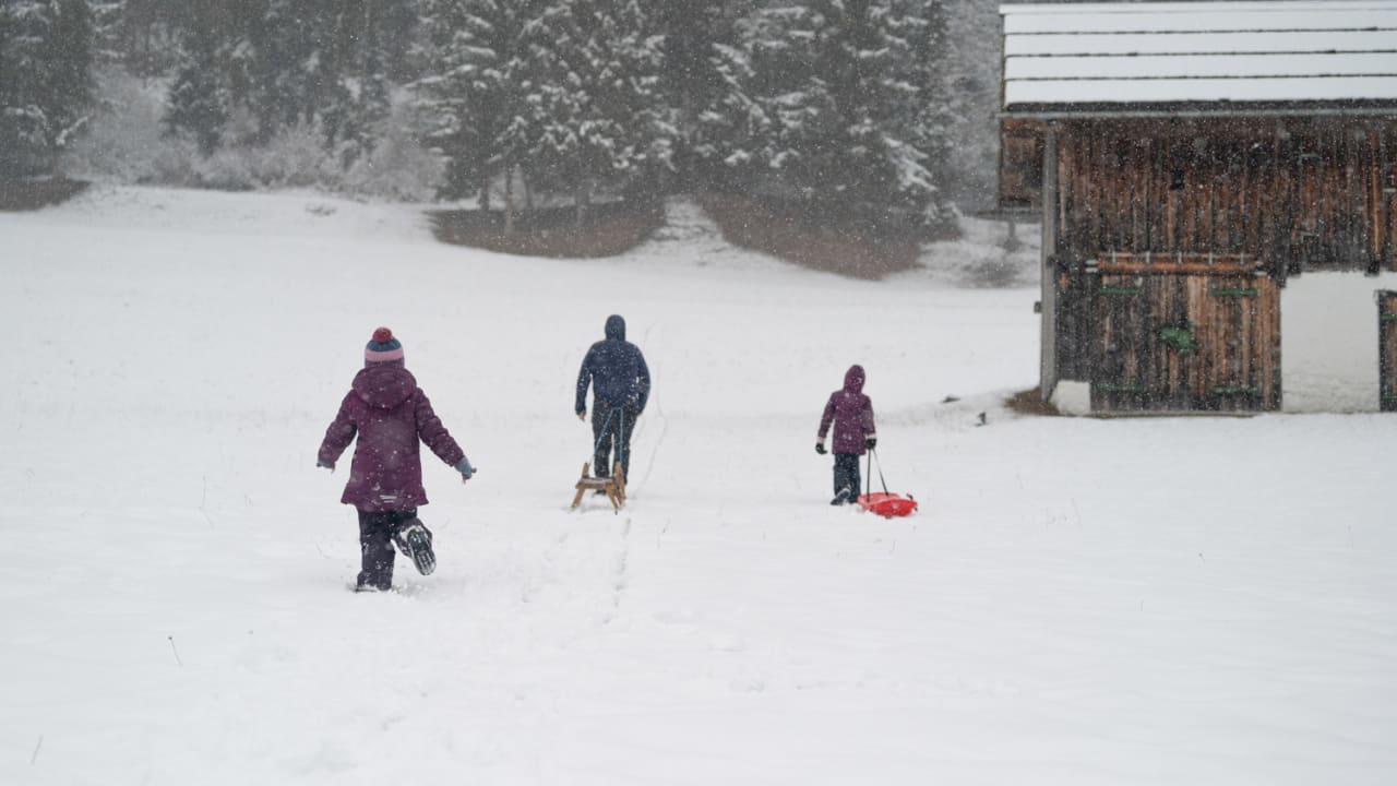 Familien mit Rodel und Bob im Schnee am Weißensee, Kärnten