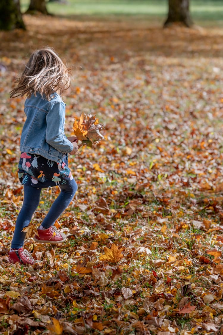 Mädchen mit Blättern im Herbst