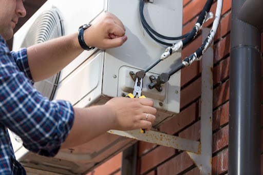 Man fixes connections on outdoor ac unit