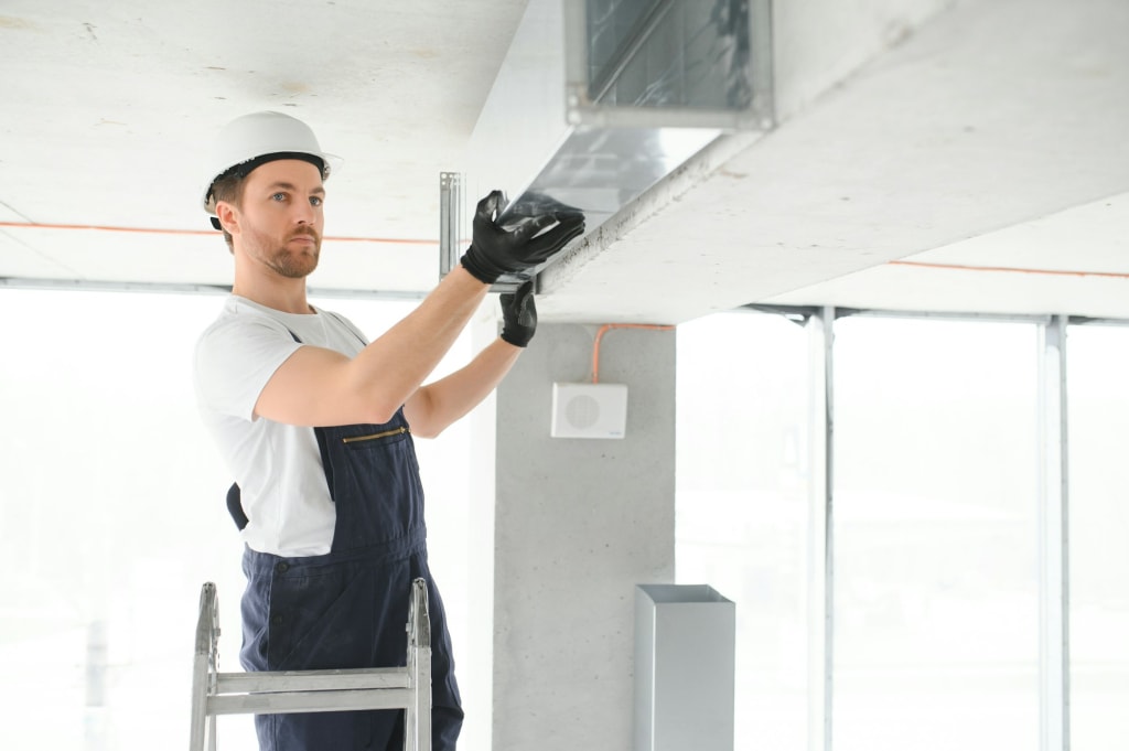 Professional HVAC Worker on a Aluminium Scaffolding Installing Air Duct