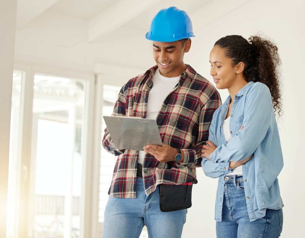 Couple planning home renovation job together, construction worker working with woman on maintenance