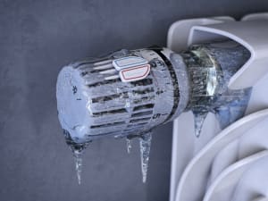 Thermostatic radiator valve with icicles. Energy crisis, sturning off heating
