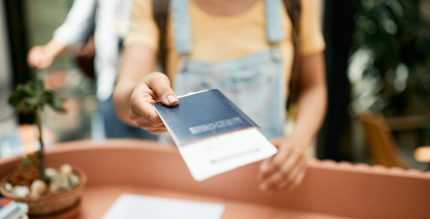 Traveler handing over a U.S. passport at a counter, using passport as proof of identity for REAL ID requirements.
