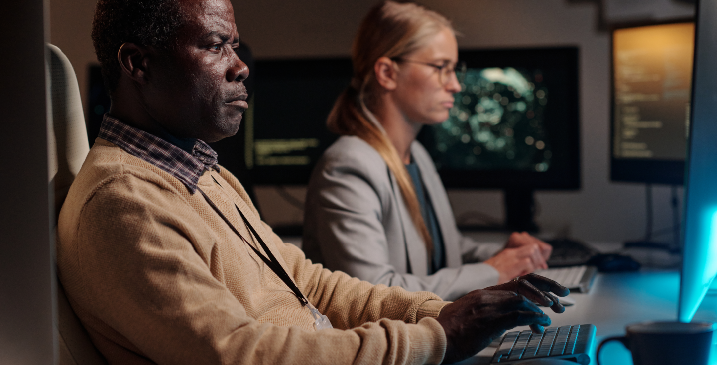 Two professionals working on computers processing online applications for certified California birth and death records.