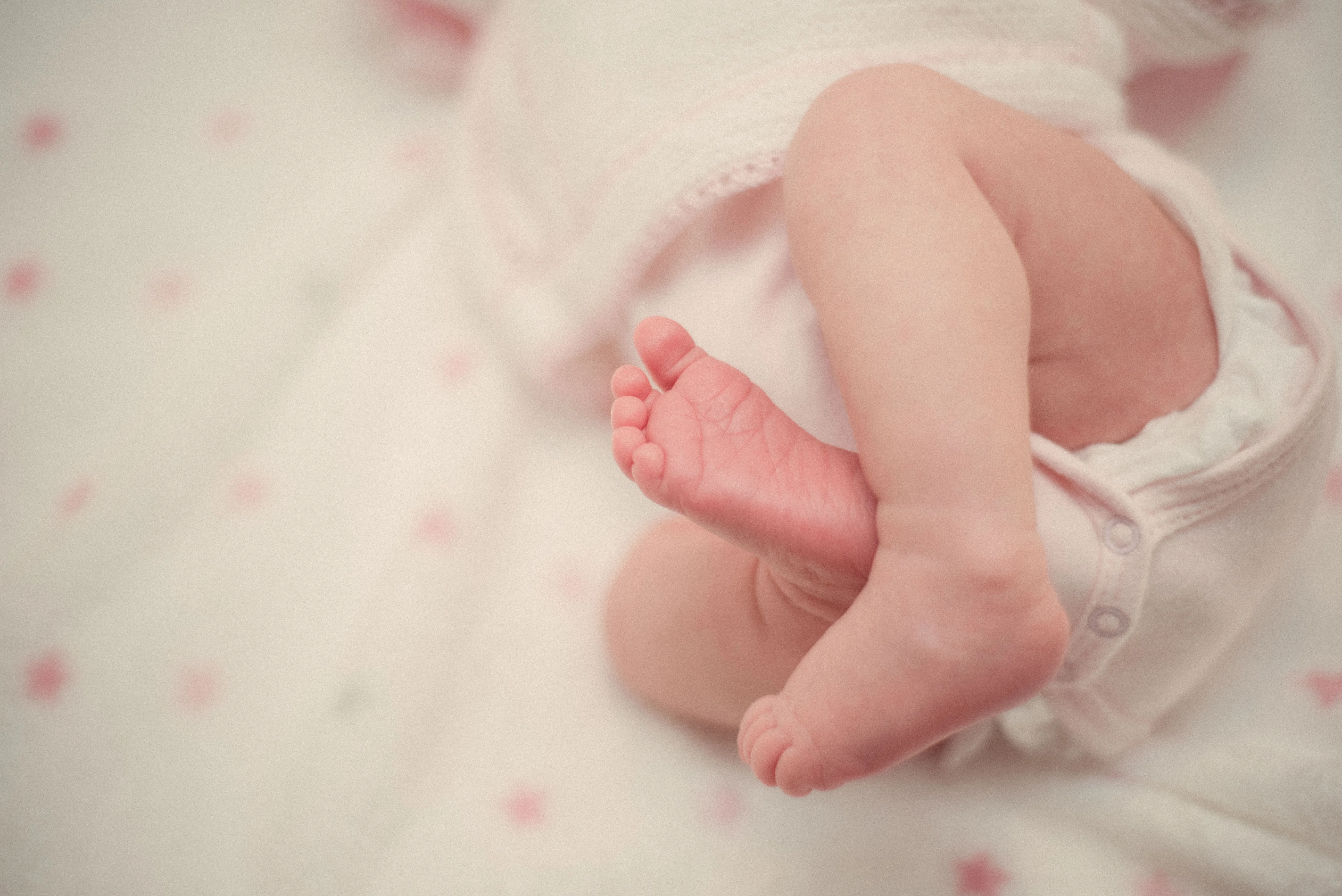The tiny feet of a newborn laying on a white blanket