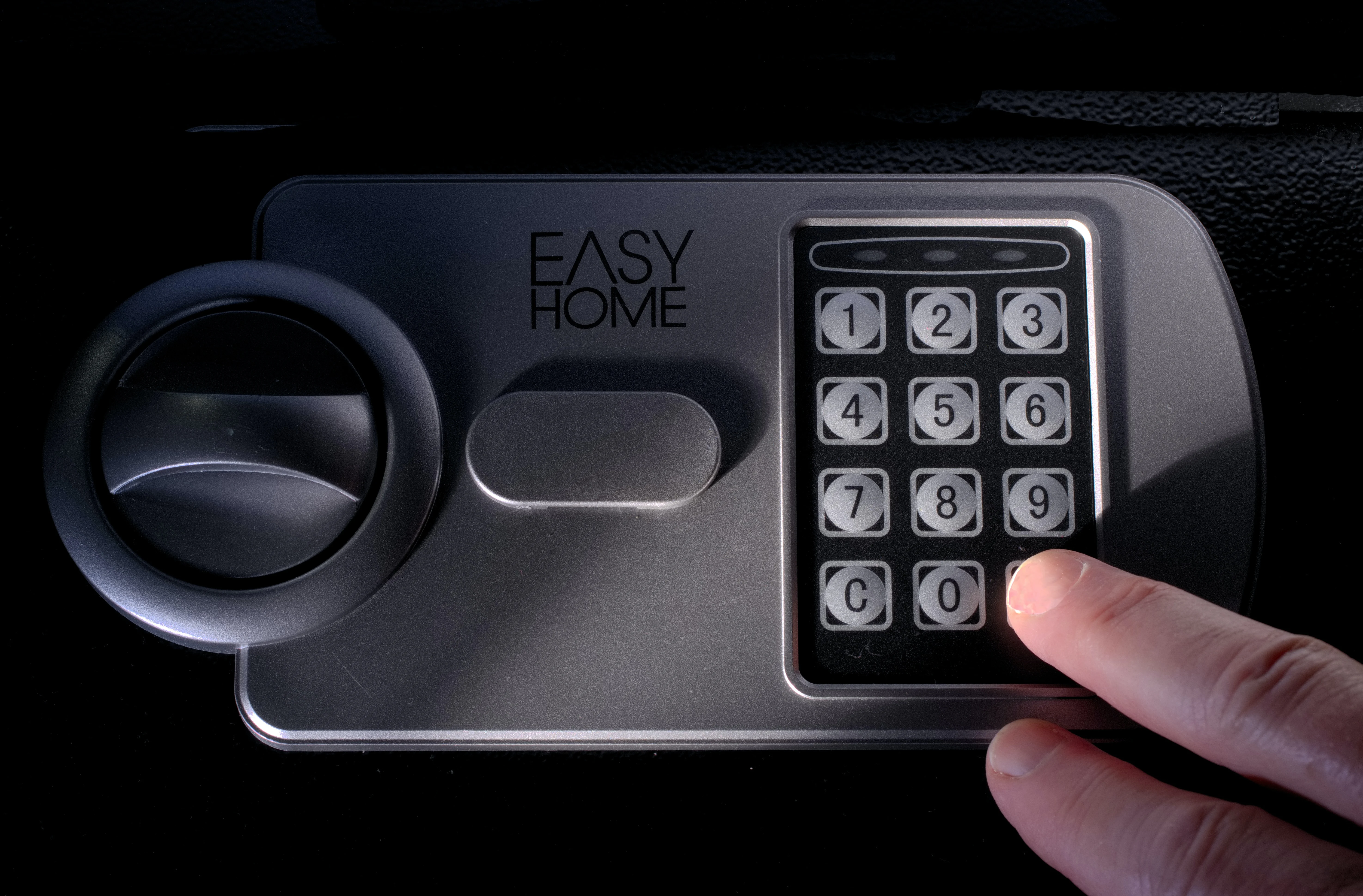 A person’s fingers pressing a dial pad of a home safe