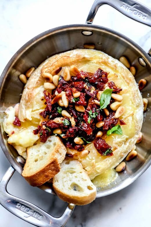 Cranberry Baked Brie Topped with Sundried Tomatoes, and Pine Nuts served with Crackers or Baguette