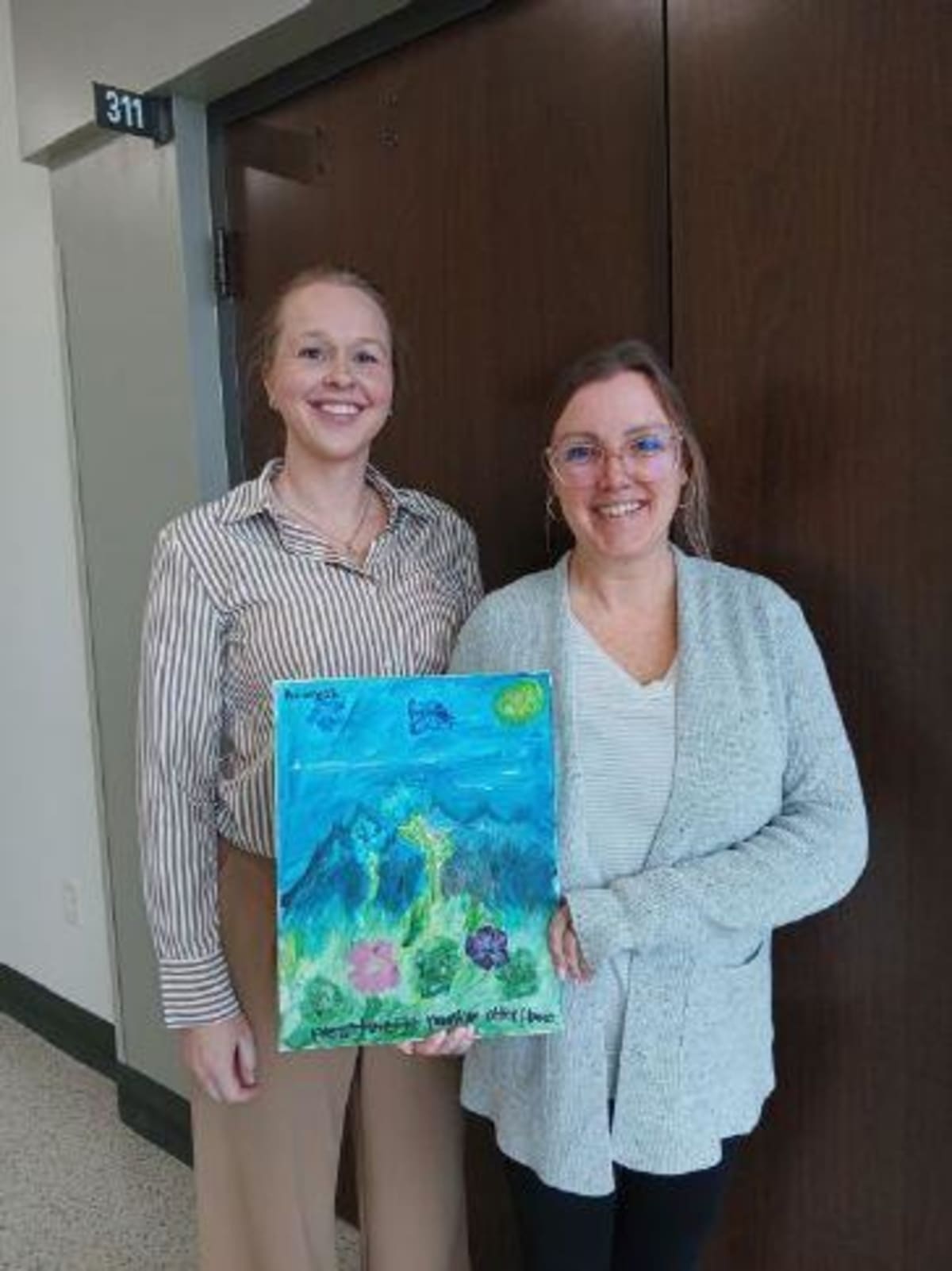 Two women holding child's painting at Friends of CASA fundraiser in Findlay Ohio