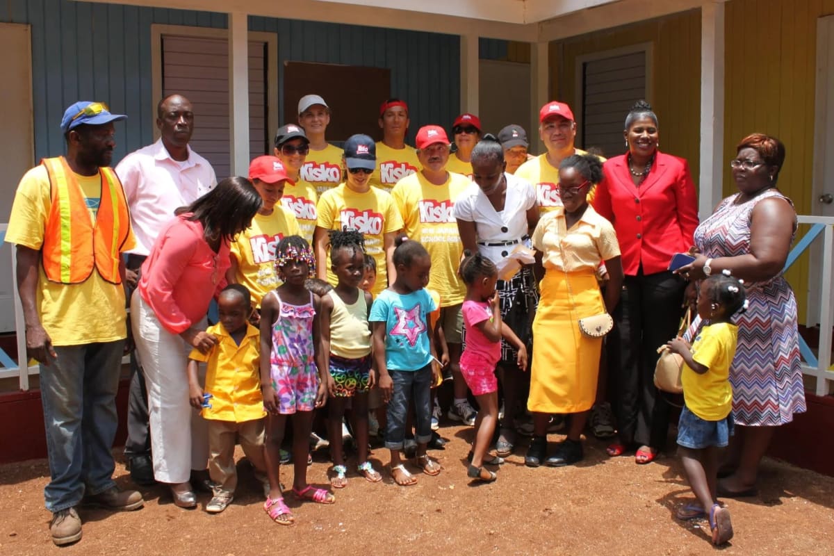 Volunteers working together to rebuild concrete school classrooms in rural Jamaica under sunny skies