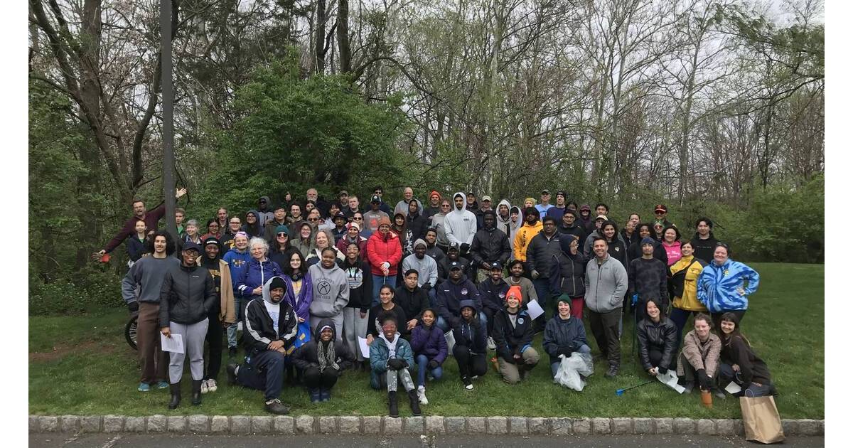 Volunteers in gloves collecting trash and debris along a stream bank during community cleanup event