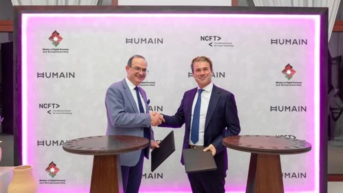 Jordanian and Saudi Arabian officials shaking hands at technology conference signing AI partnership agreement