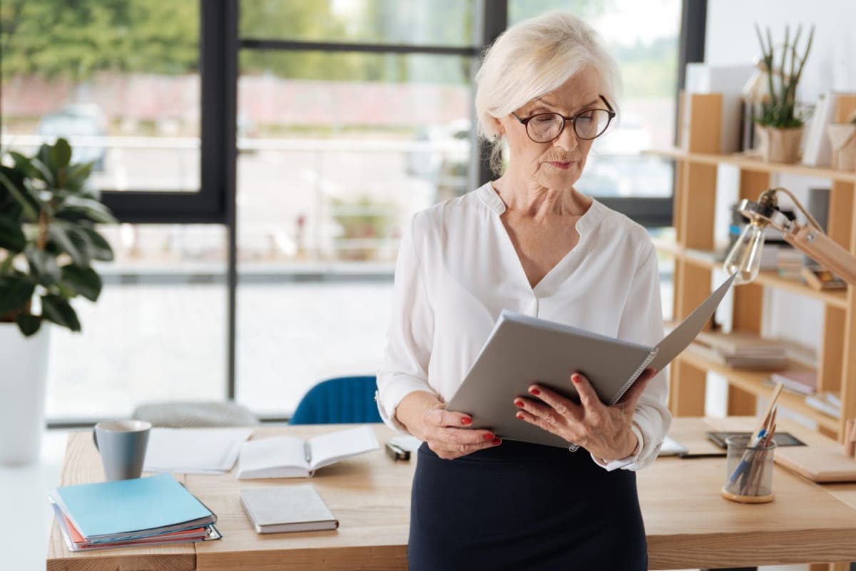 Smiling nurse in scrubs holding house keys and retirement savings documents
