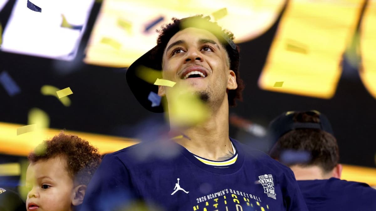 Michigan Wolverines basketball players celebrating with championship trophy on confetti-covered court