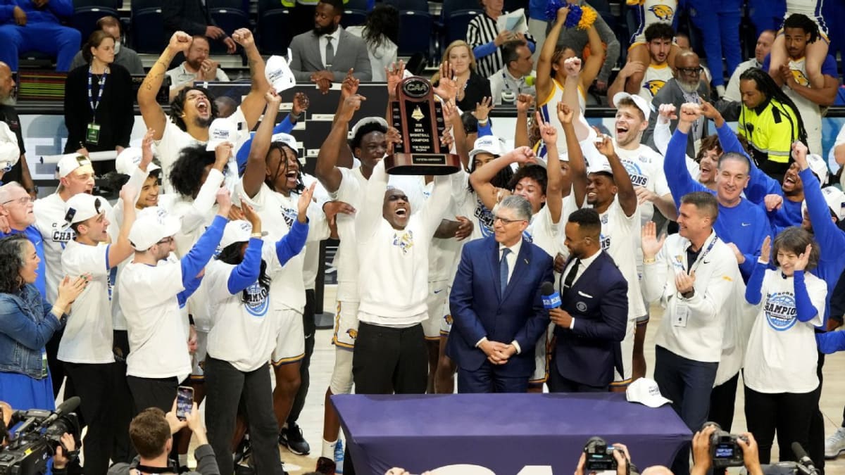 Hofstra basketball players celebrating championship victory on court after defeating Monmouth