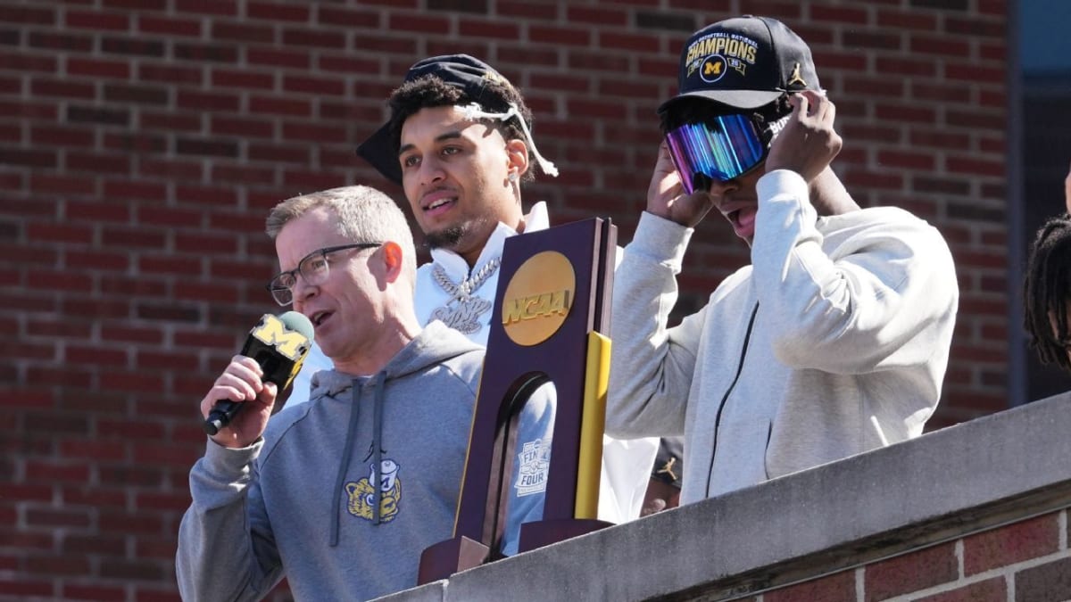 Michigan Wolverines basketball team celebrating with national championship trophy surrounded by cheering fans