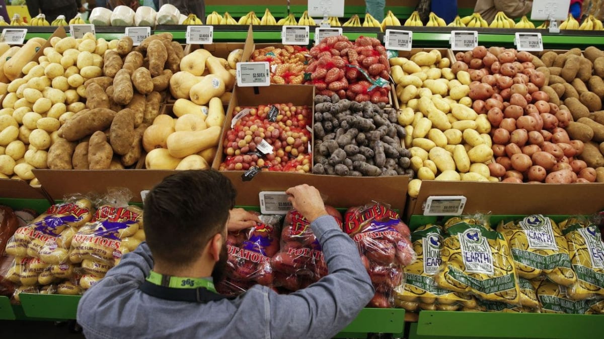 Shopper examining food date labels in California grocery store produce section