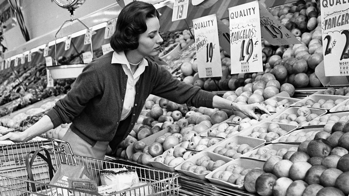 Black and white vintage photograph of shoppers browsing grocery store aisles in the 1960s