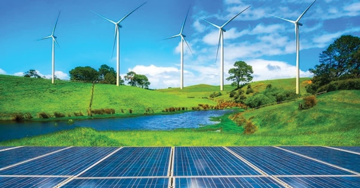 Solar panels stretching across African landscape with wind turbines in background under bright sun