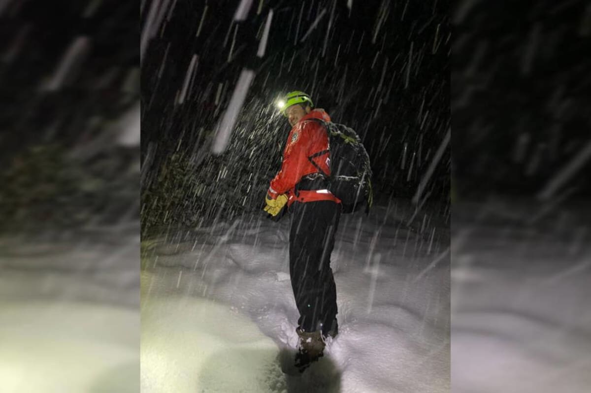 Rescue team members navigating snowy mountain terrain during nighttime search operation on 5040 Peak trail