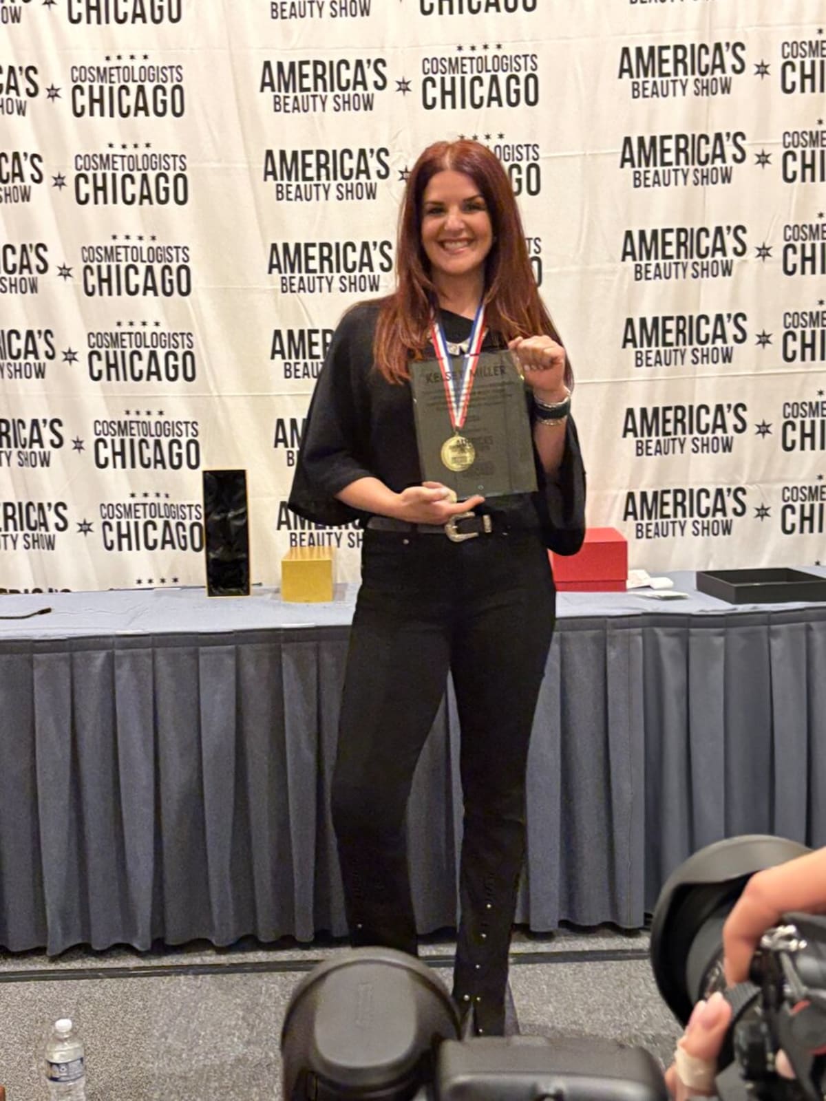 Kelsey Miller holding gold medal and plaque at America's Beauty Show awards ceremony
