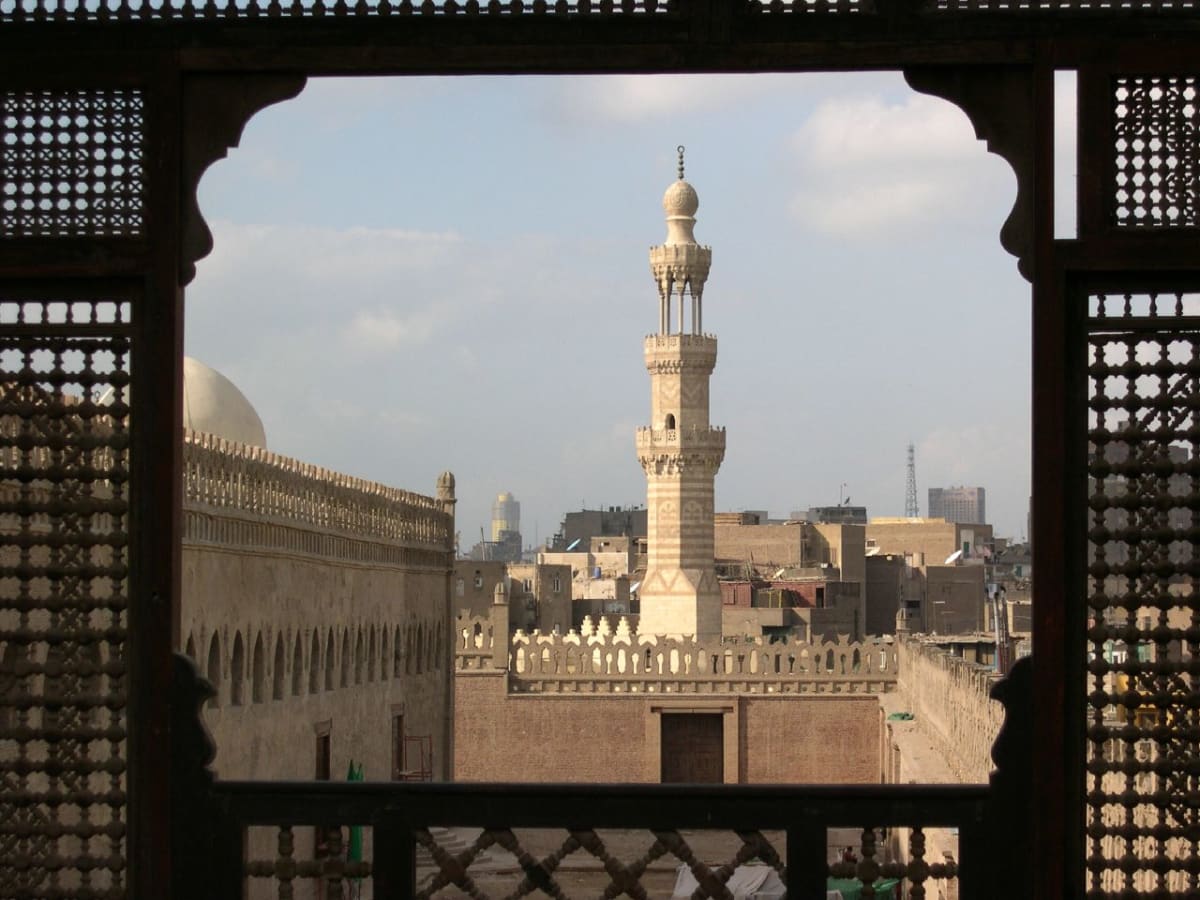Historic Islamic mosque in Cairo undergoing careful restoration work with green spaces nearby