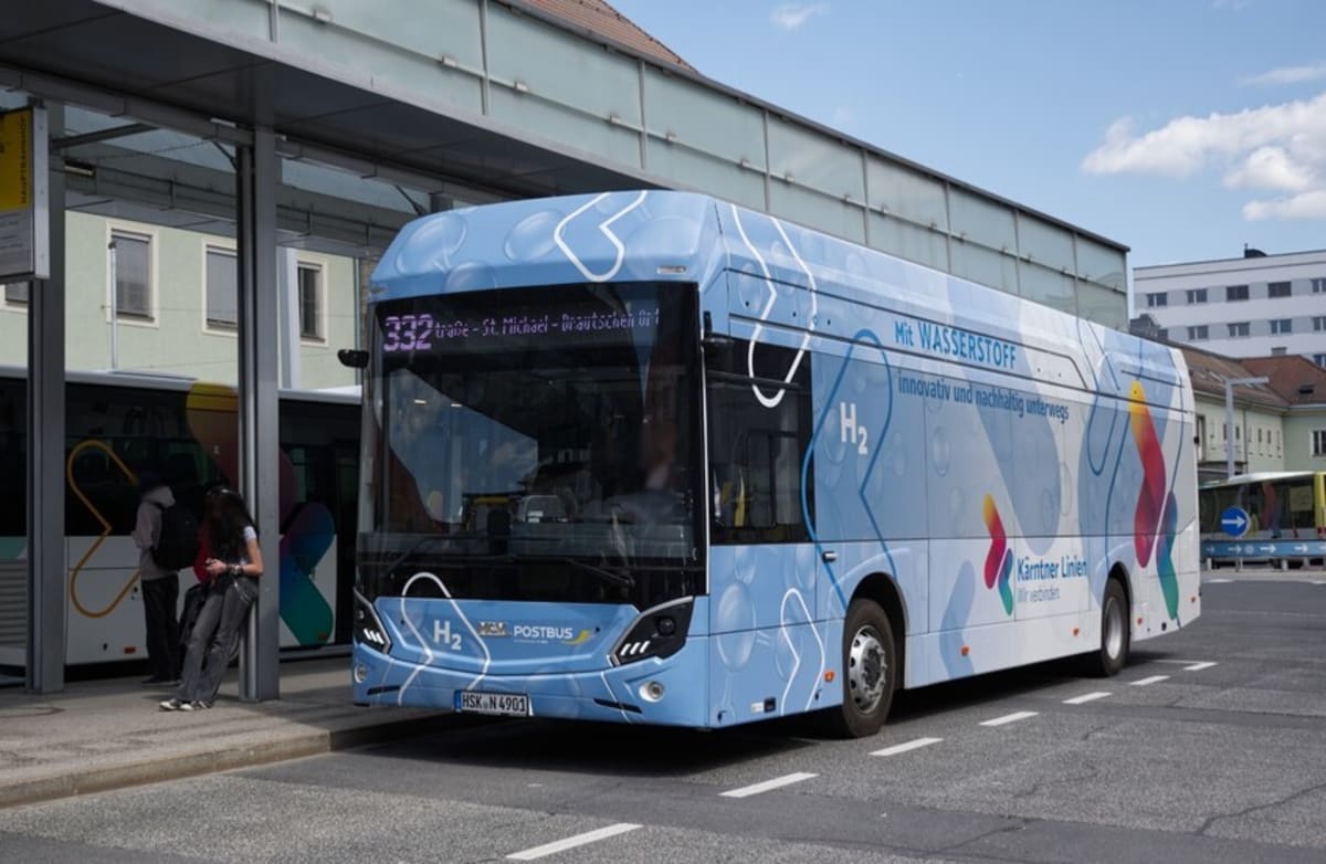 Modern hydrogen-electric bus on Austrian mountain road with Alpine peaks in background