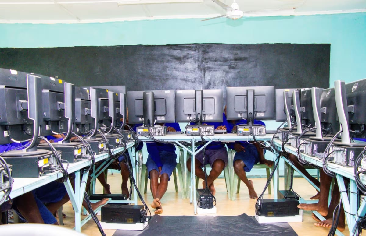 Young students in Kenya learning computer coding and robotics skills in prison classroom setting