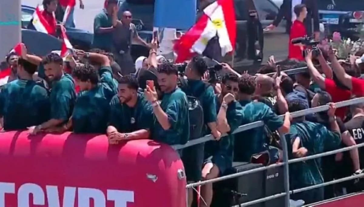 Egyptian soccer fans surround open-top bus carrying national team through crowded New Alamein streets