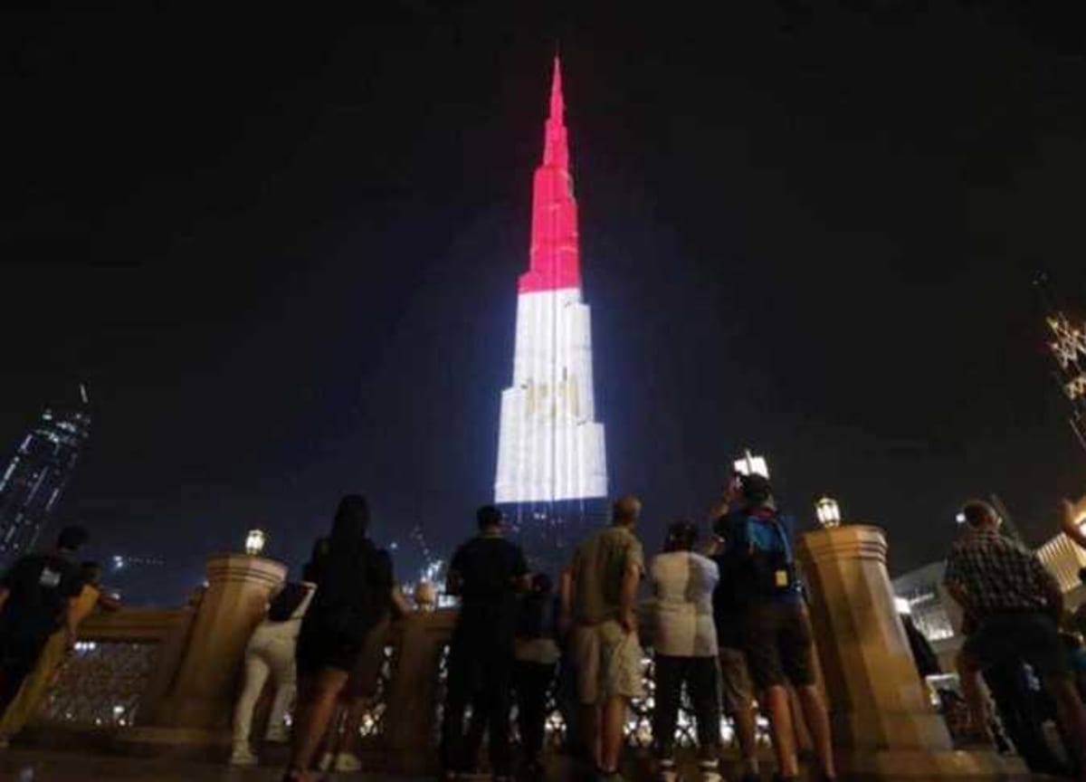 Burj Khalifa tower in Dubai illuminated with red white and black Egyptian flag colors at night