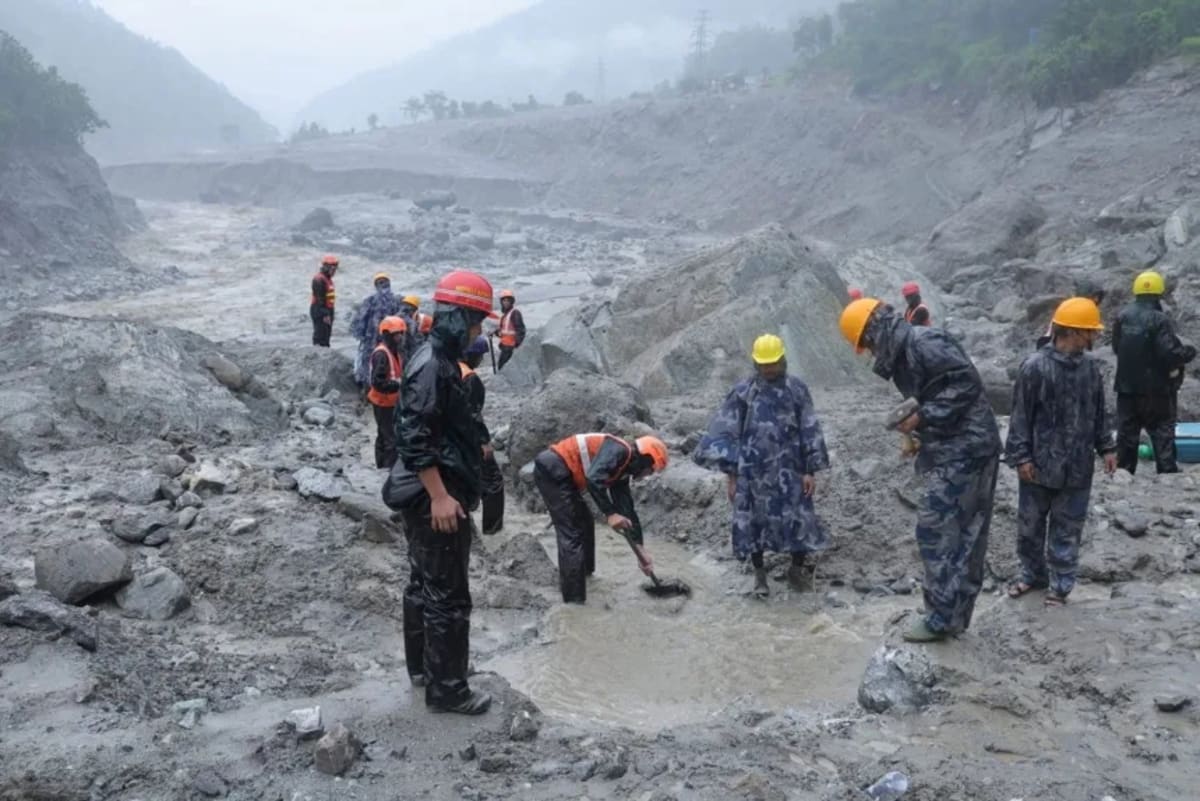 ** Rescue workers conducting operations near flooded hydropower tunnel entrance in Nepal mountains