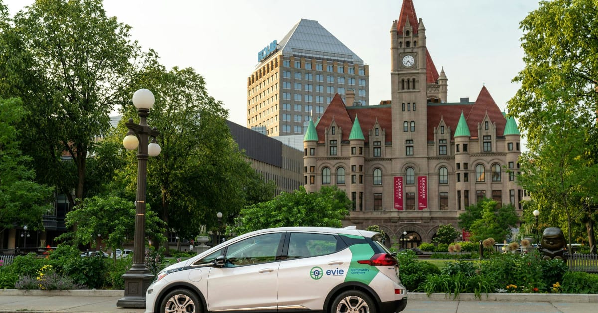 White Hourcar electric vehicle parked on city street near downtown St. Paul building
