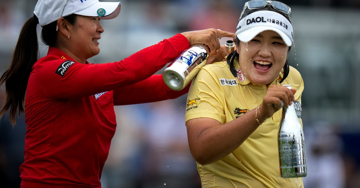 Haeran Ryu celebrating with championship trophy while being sprayed with champagne at Hazeltine