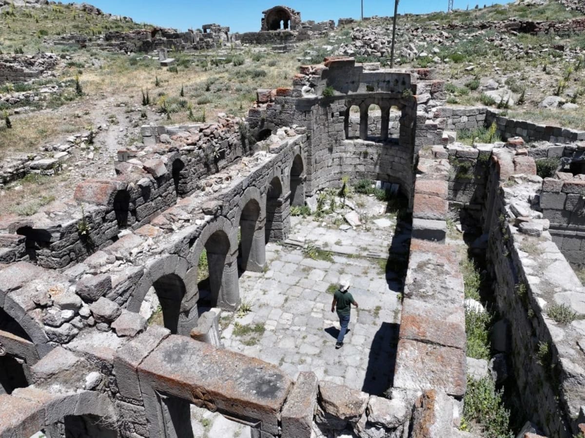 Ancient stone Byzantine church ruins scattered across volcanic hillside in central Turkey