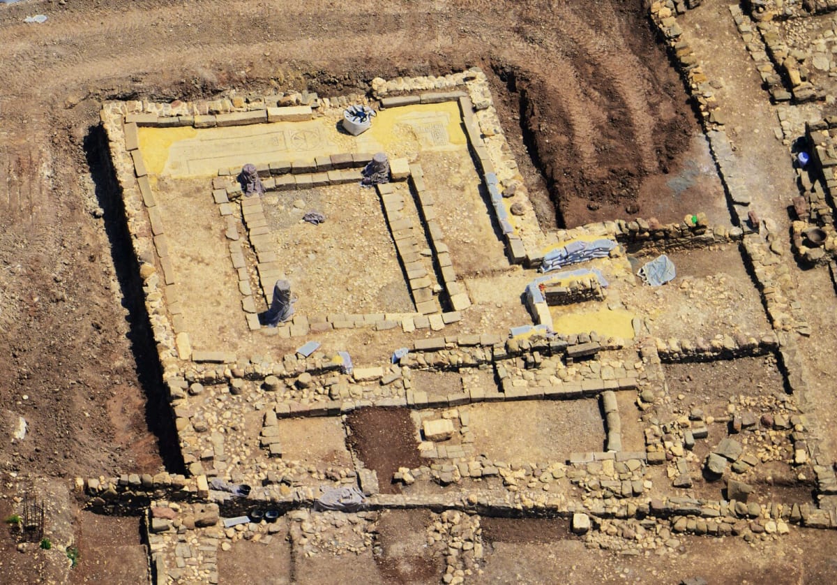 Interior view of first century Magdala synagogue showing mosaic floor and stone benches
