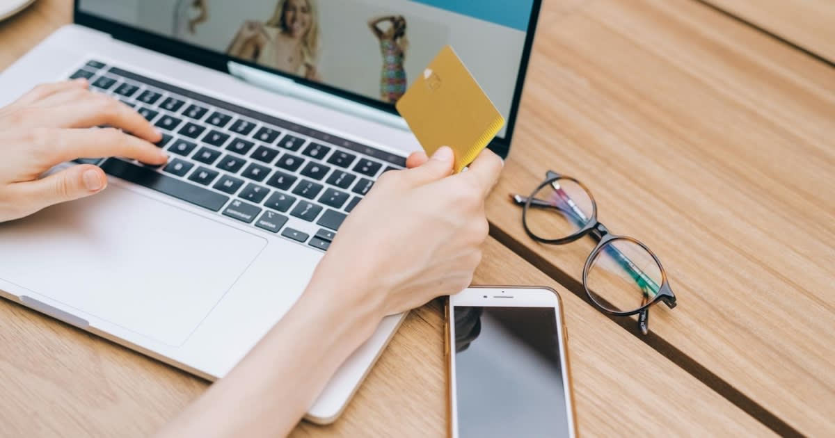 Person shopping online using smartphone with delivery boxes in background