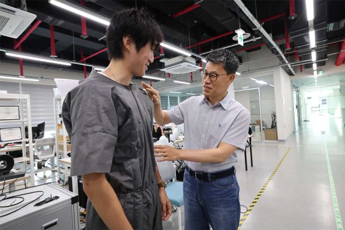 Researcher demonstrates self-dressing robotic jumpsuit that unfolds over wearer's body at KAIST laboratory